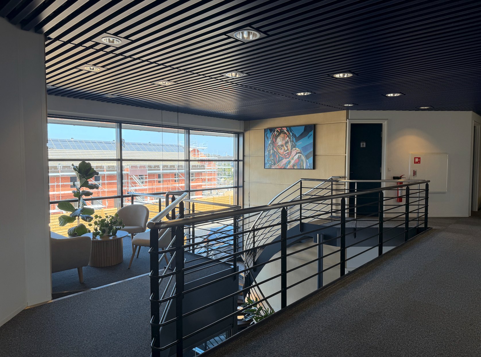 Opholdsområde på first sal med lænestole, plante og maleri