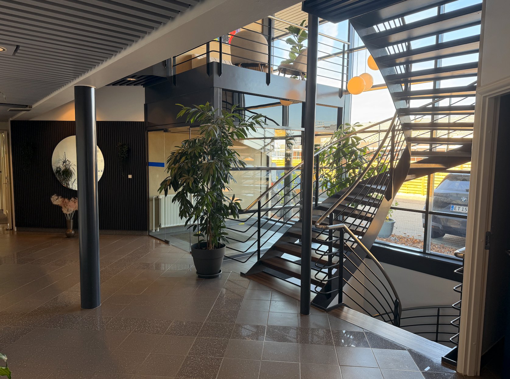 Trappehus med beplantning, lounge på first sal og kig ud mod parkeringspladsen